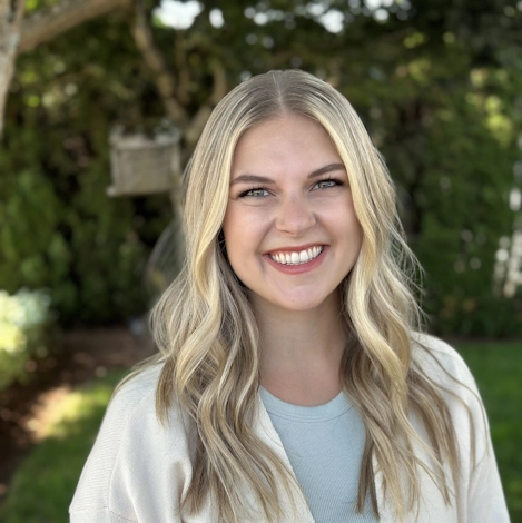 Portrait of a smiling woman outdoors with greenery in the background