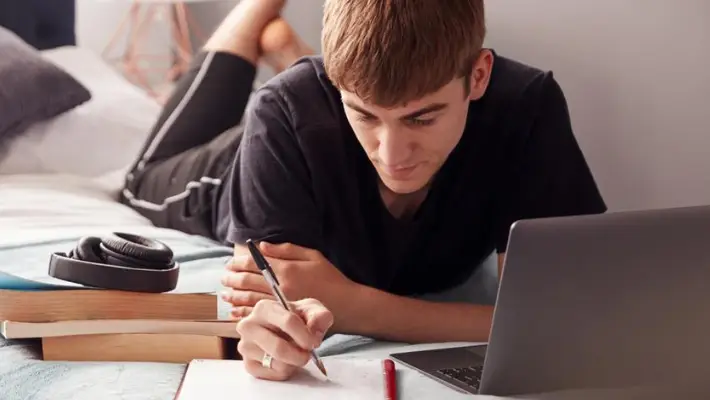 Student taking online classes at home with laptop. 