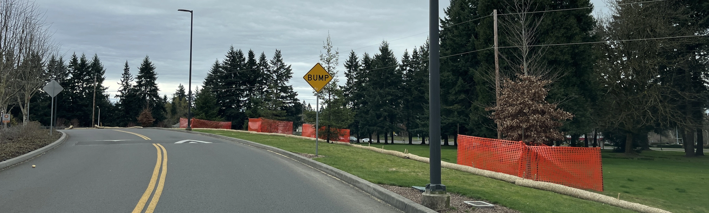 Curved road with construction fences and a warning sign