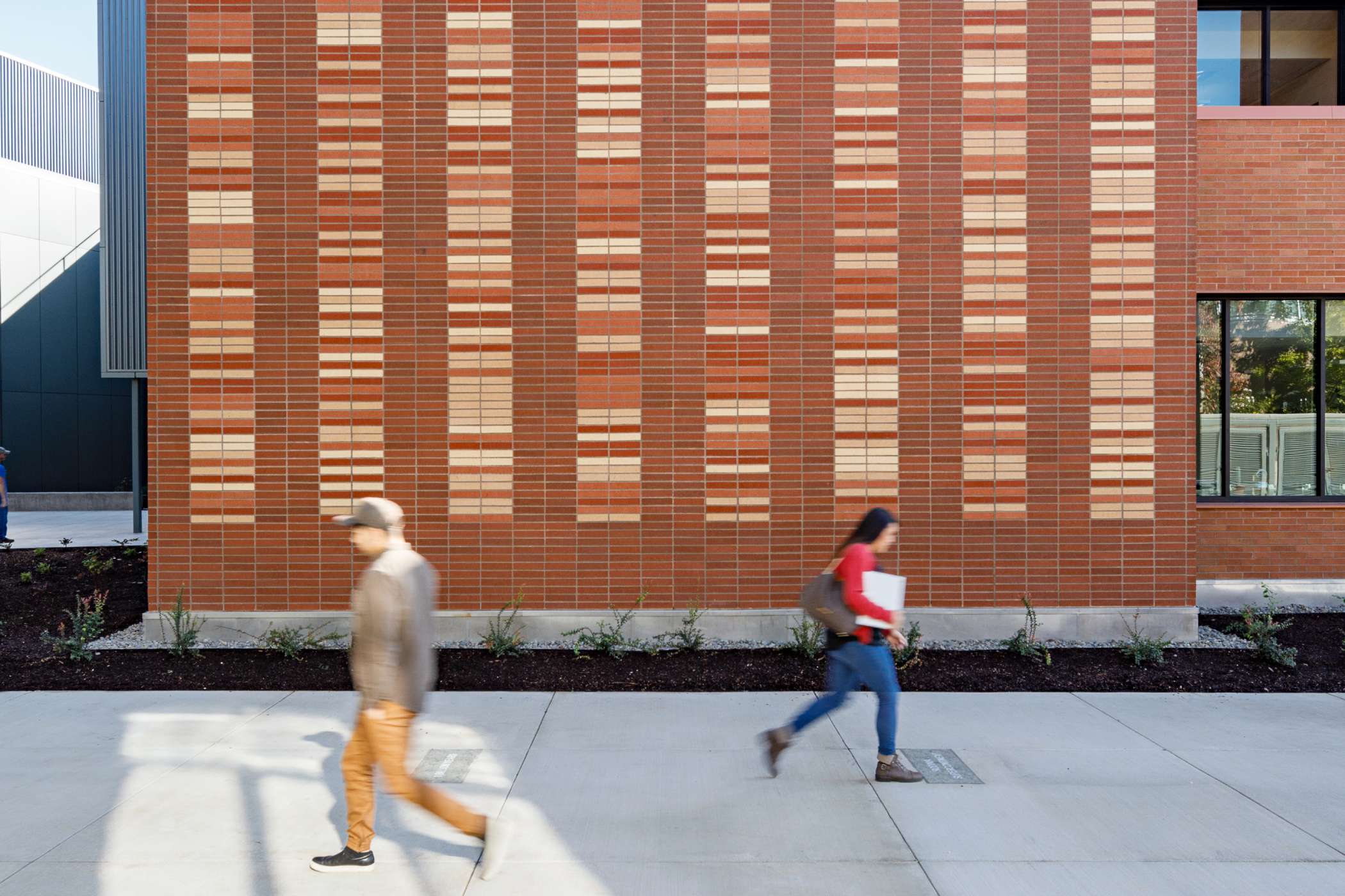 Two students walking past each other outside DeJardin Hall Two students walking past each other outside DeJardin Hall