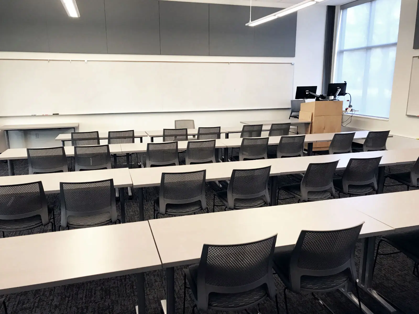 Rows of chairs and tables with a podium in front of a whiteboard in Harmony Campus classroom