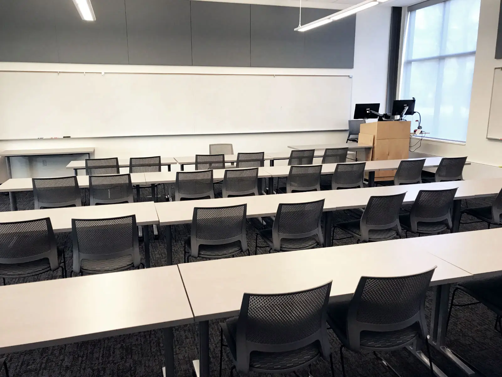 Rows of chairs and tables with a podium in front of a whiteboard in Harmony Campus classroom Rows of chairs and tables with a podium in front of a whiteboard in Harmony Campus classroom