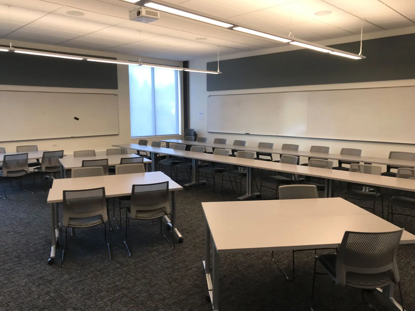 Two rows of tables and chairs in front of several separate tables in a Harmony campus classroom