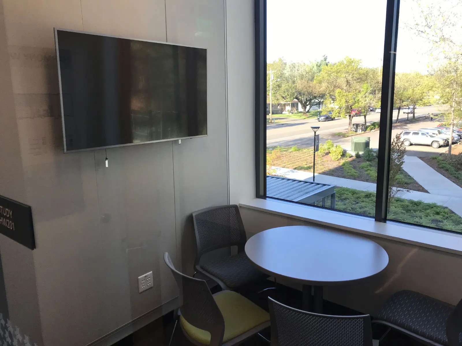 A TV screen in front of a window and small table with chairs in the Harmony campus conference room