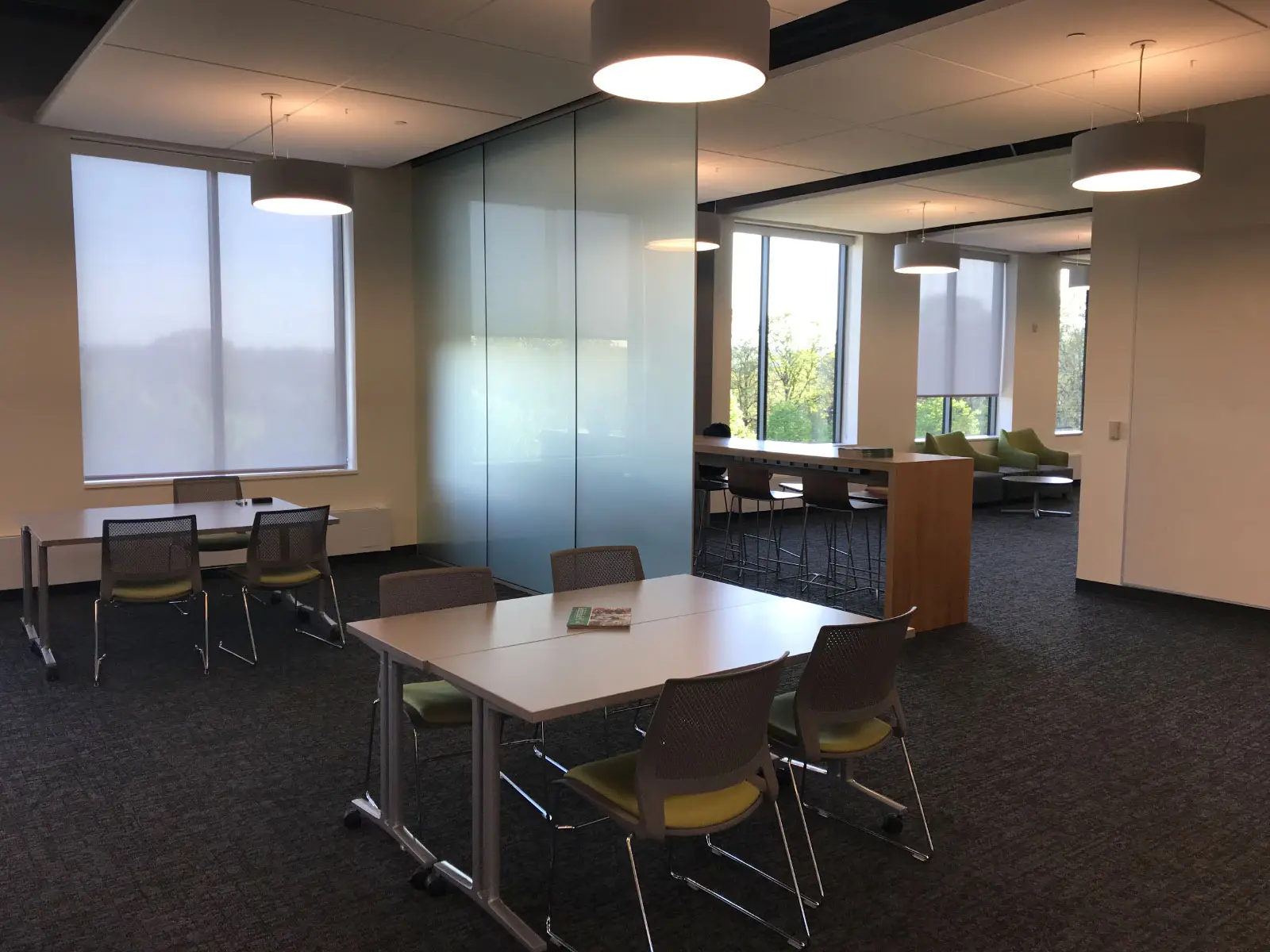 Several small meeting tables with chairs in a Harmony campus lobby