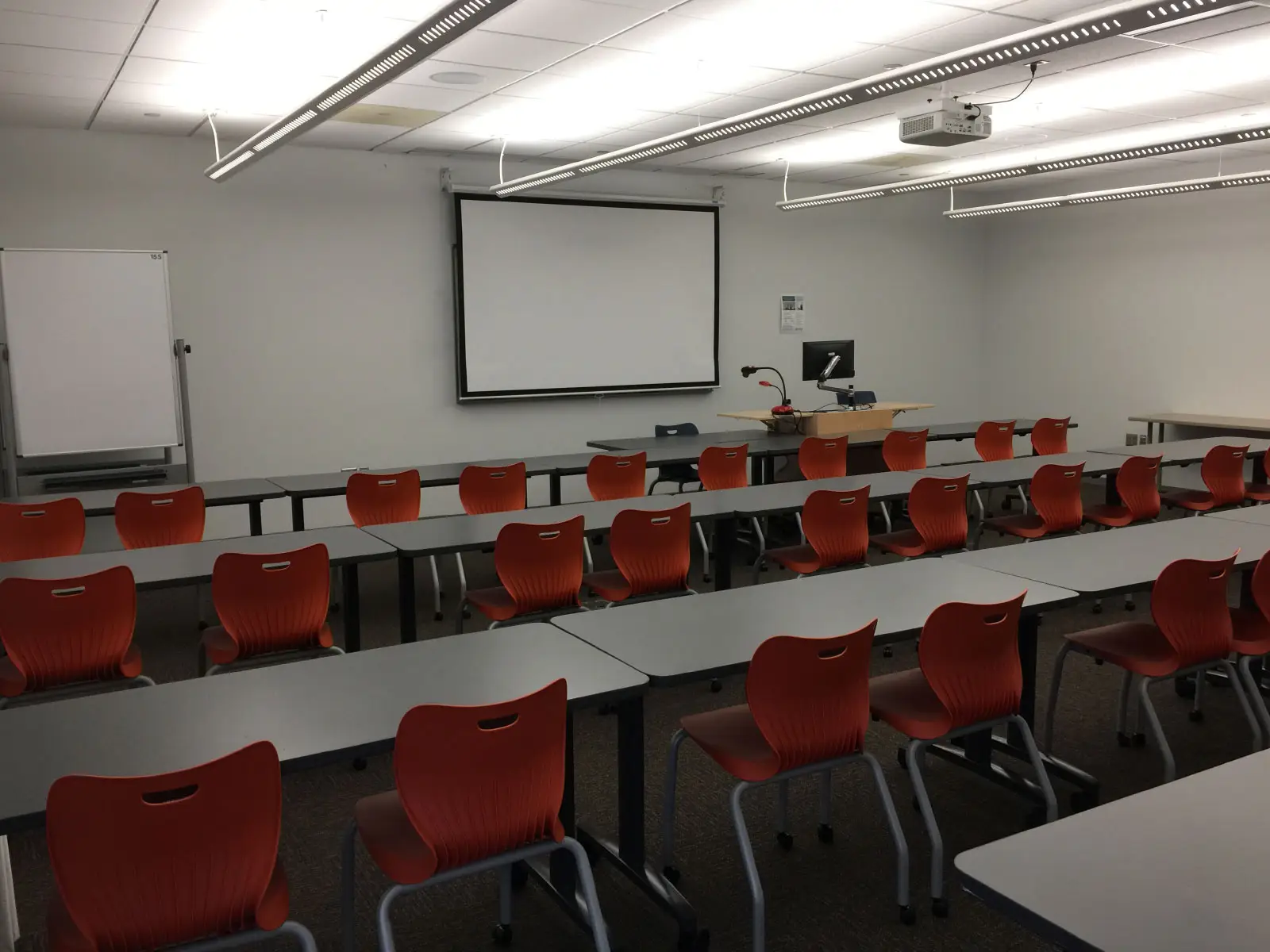 Rows of orange chairs and tables in front of a podium and projector in classroom W155 on the WIlsonville campus Rows of orange chairs and tables in front of a podium and projector in classroom W155 on the WIlsonville campus