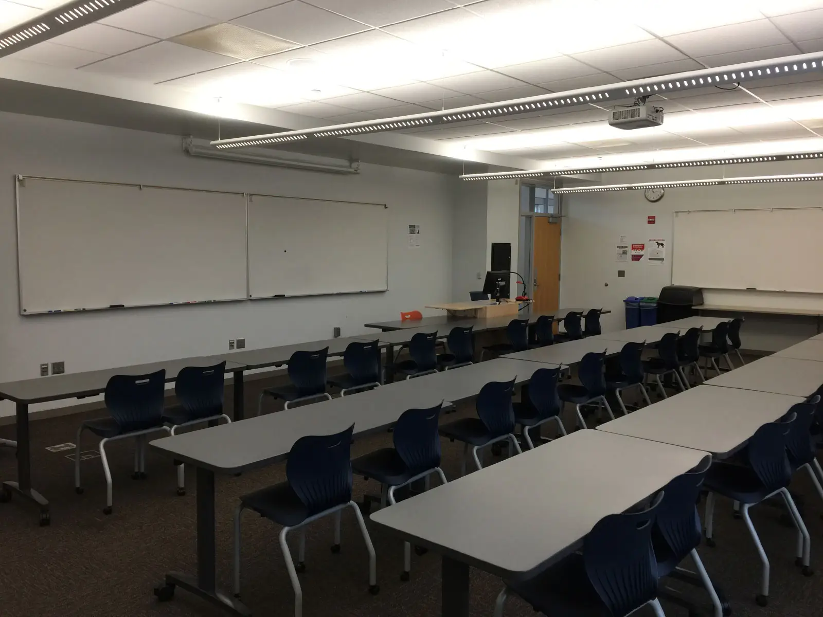 Rows of blue chairs and tables in front of a podium and white board in classroom W210 on the WIlsonville campus Rows of blue chairs and tables in front of a podium and white board in classroom W210 on the WIlsonville campus