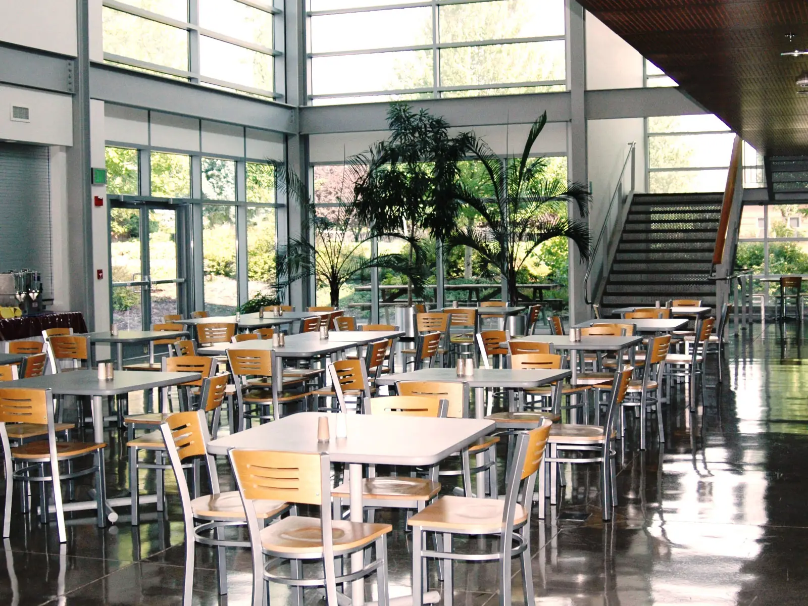 Rows of tables with chairs in the open commons area next to a set of stairs on the Wilsonville campus Rows of tables with chairs in the open commons area next to a set of stairs on the Wilsonville campus