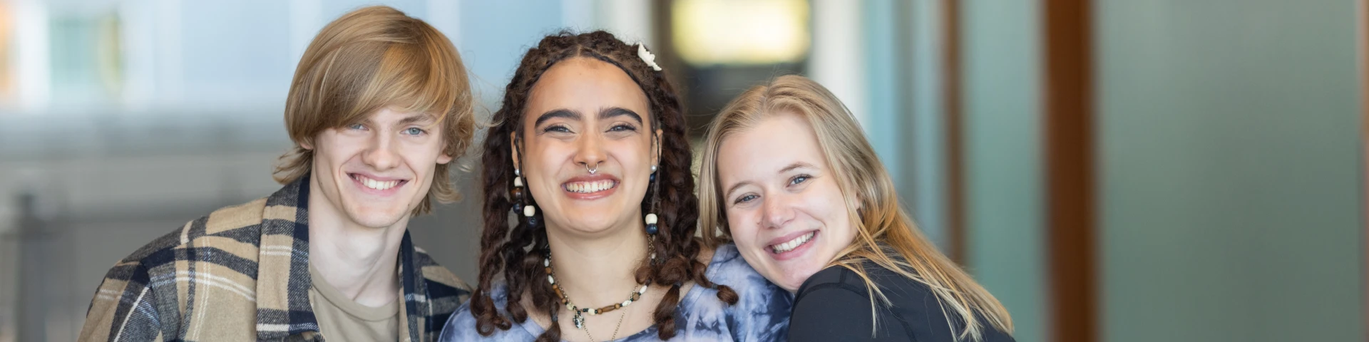 Three CCC students pose and smile in a campus hallway