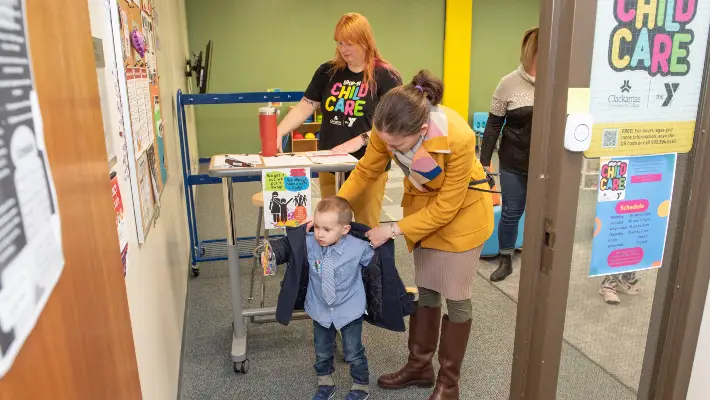 Woman taking coat off child in the Child Care office