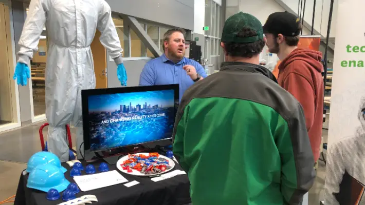 Two fair-goers visiting a booth about hydraulics