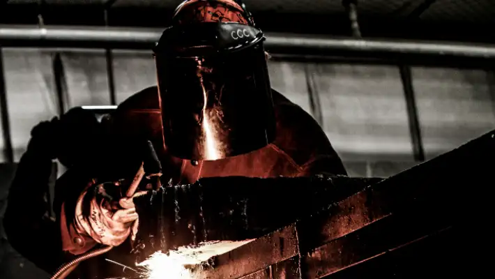Student in welding mask using a blowtorch