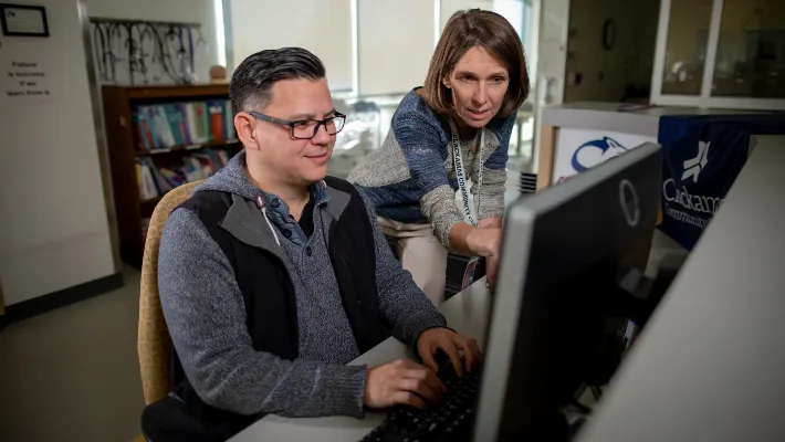 A teacher assisting a student on a computer