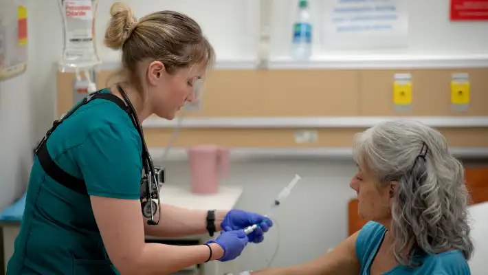 Student in scrubs giving patient an IV