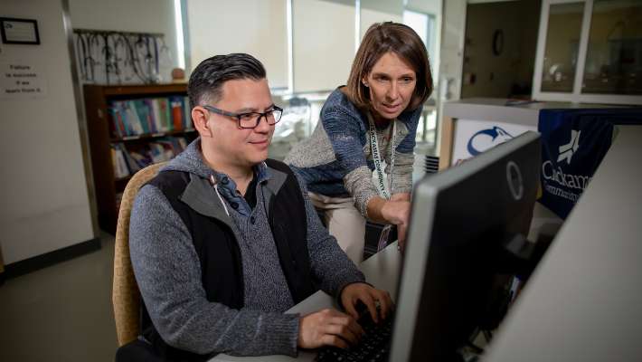 A teacher helping a student on the computer