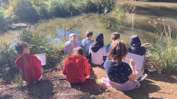 journaling kids with pencils and paper observe a duck in the pond at CCC's Environmental Learning Center