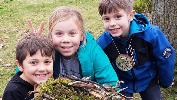 Three kids smiling with their outdoor project